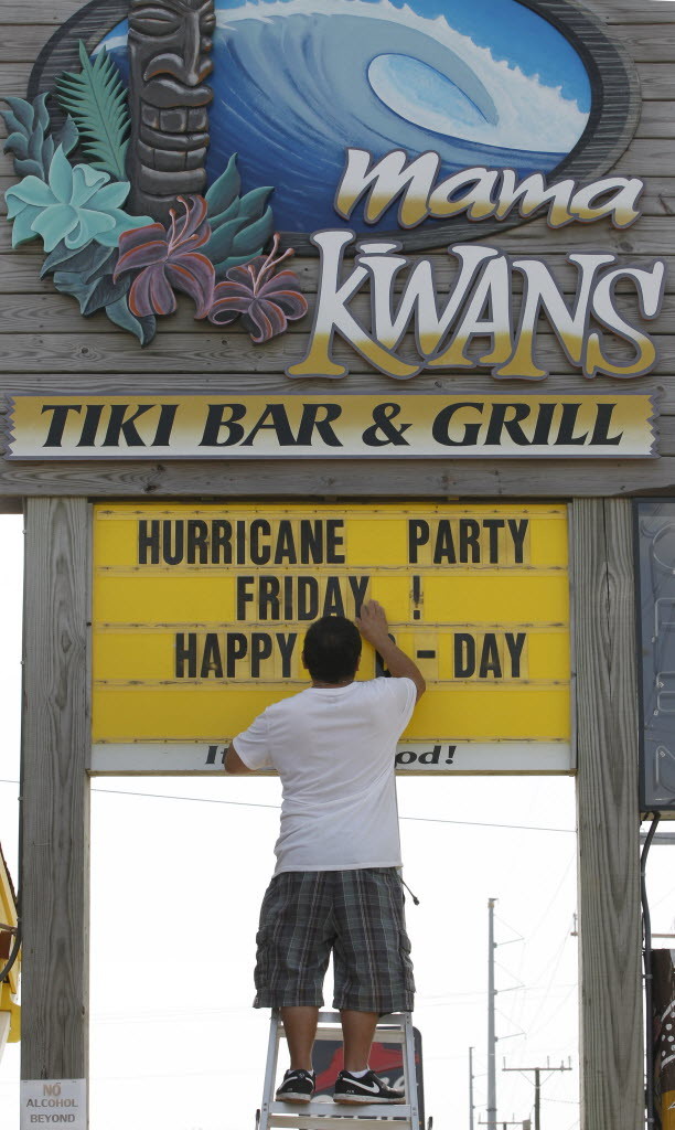 A North Carolina man adjusts a sign advertising a hurricane party during Irene in 2011. (AP Photo/Charles Dharapak)
