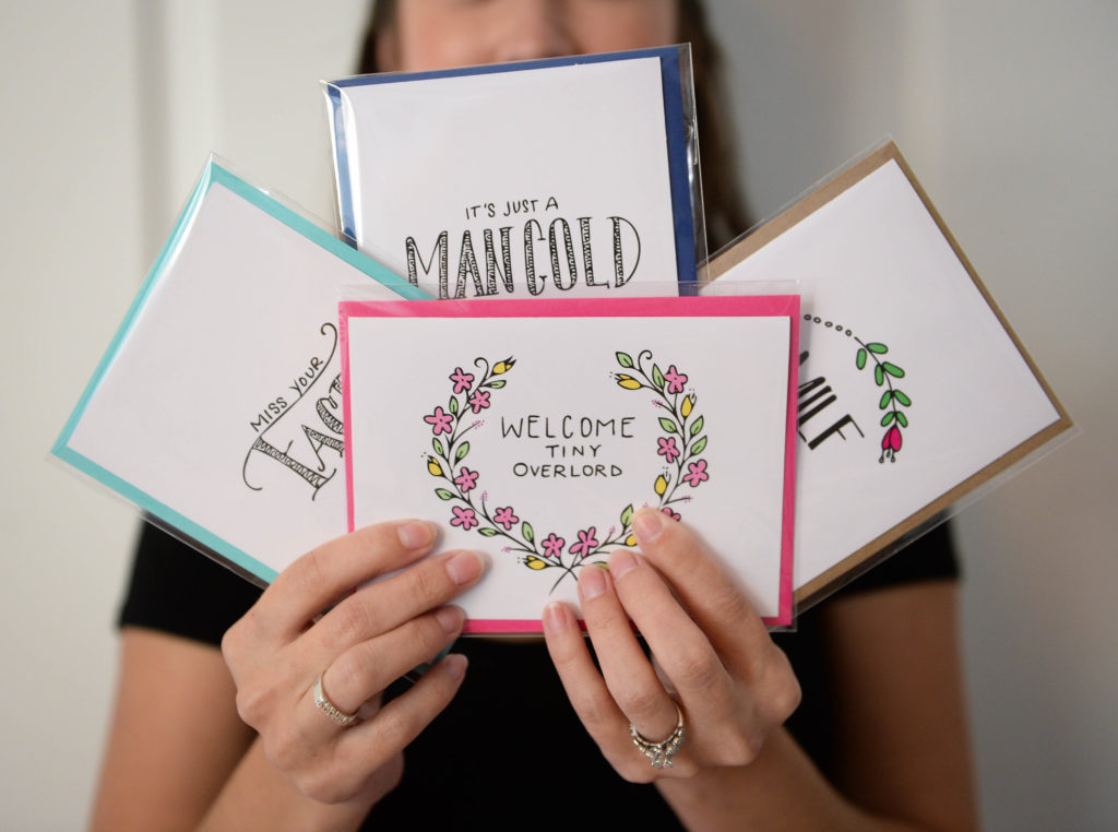 Bailey Spasovski, 29, of Cheek & Pen Paper Co., holds up a few of her favorite cards. Herald-Tribune staff photo / Rachel S. O'Hara