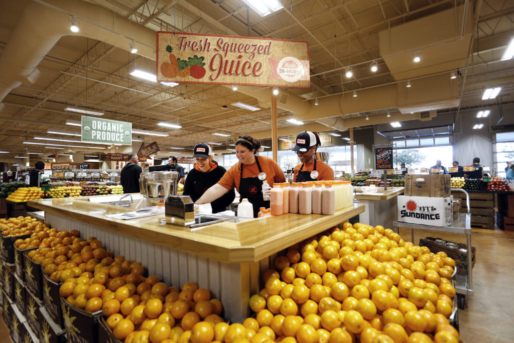 From left to right, employees Sable Herrera, Chassidi Garrett and Shekirra Thompson, pour fresh-squeezed juices for customers to sample/purchase, Tuesday, January 6, 2015 during the grand opening of Lucky's Market at 1459 NW 23rd Avenue in Gainesville, Fla. Erica Brough/Gainesville Sun