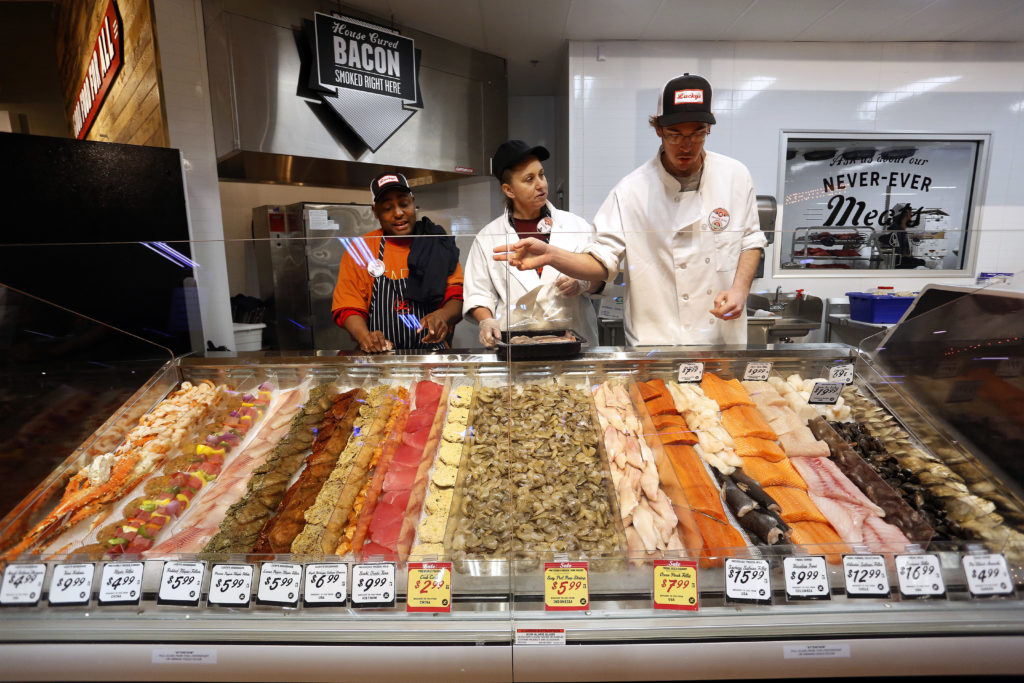 From left to right, seafood specialists Rupert Heard, Claudia Tucciarone and Evan Gerhart organize the seafood display, Tuesday, January 6, 2015 during the grand opening of Lucky's Market at 1459 NW 23rd Avenue in Gainesville, Fla. Erica Brough/Gainesville Sun